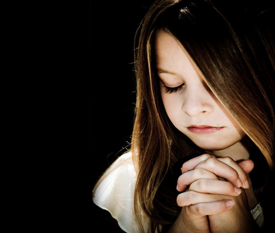 A little girl prays to Jesus