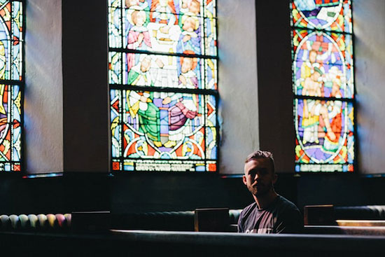 A man sitting in a Seventh-day Adventist Church that has stained glass windows