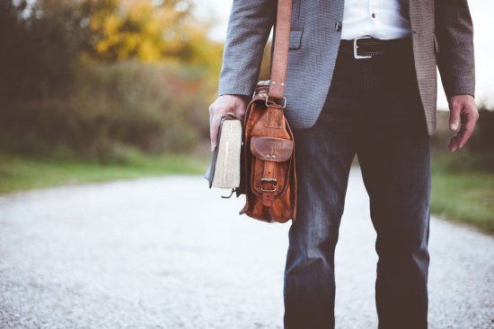 Adventist Evangelist holding Bible and brown bag, going to share the truths of the Bible with someone else