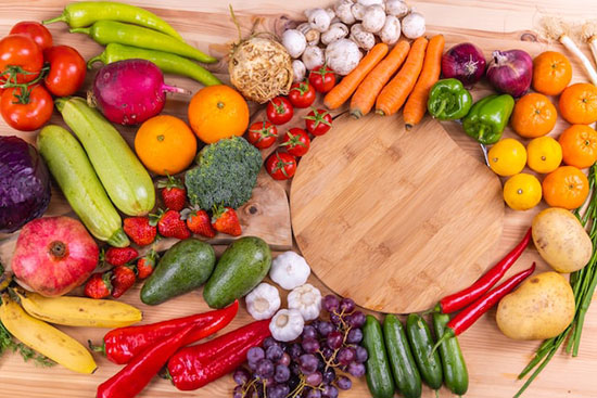 A wooden table covered in colorful fruits and vegetables to represent the vegetarian diet of many Adventists