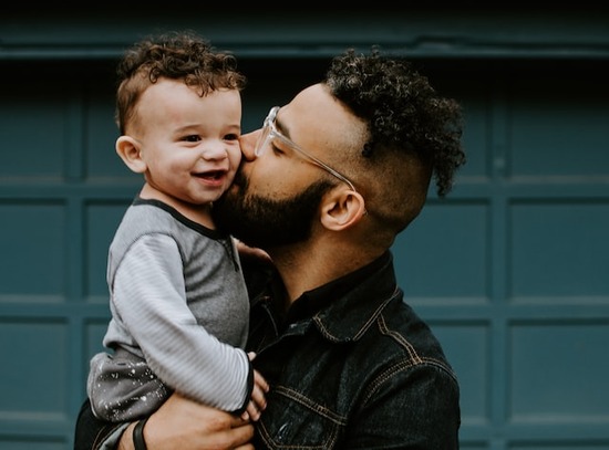 A father kissing the cheek of his little son, illustrating the love our heavenly Father has for us