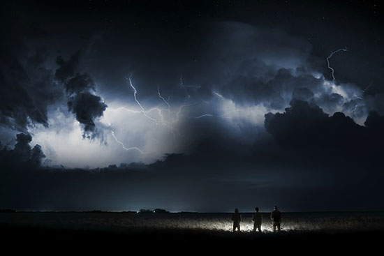People standing under a dark sky with flashes of lightning similar to the way everyone will see when Christ returns