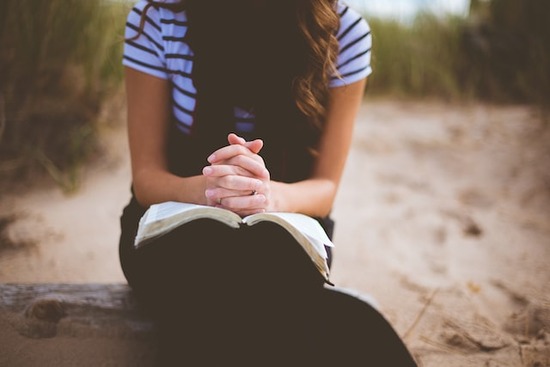 A girl reading a devotional and praying