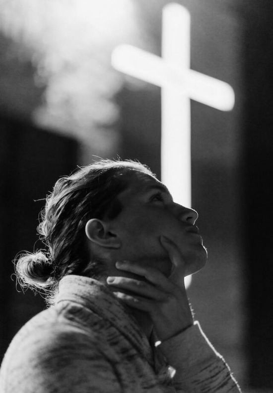 A woman looking at the cross and contemplating what Jesus did for her to provide her with eternal life