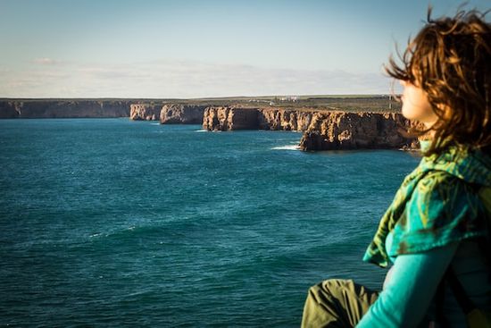 A woman sitting on a cliff near the sea and enjoying the Sabbath