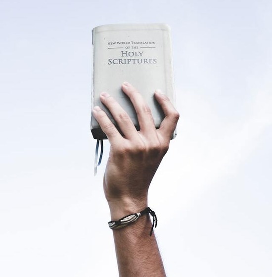 A hand holding up the Word of God to show that Scripture alone is our authority