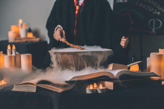 A false prophet practicing magic with a wand over a steaming bowl