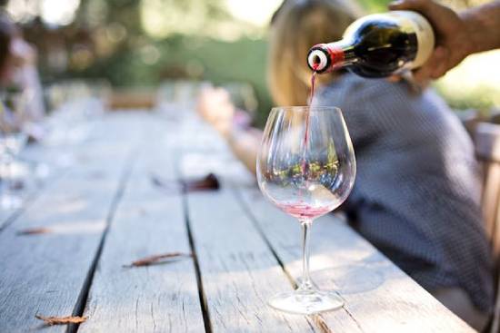 Man's hand pouring red wine into a wine glass A person pours red wine into a glass. Wine in the Bible can symbolize false teachings and clouded judgment.