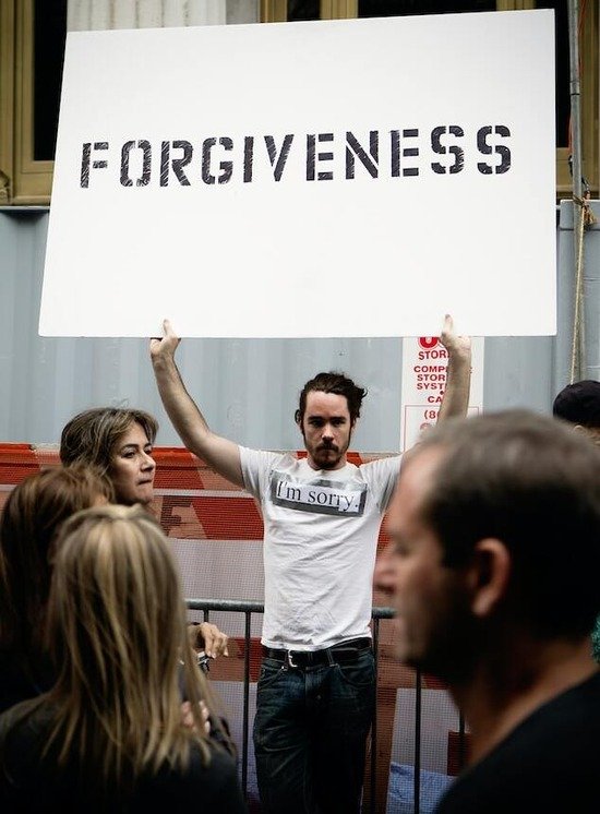 A man holding up a sign that says, Forgiveness