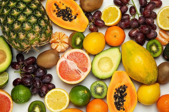 An assortment of fruit: pineapple, papaya, grapefruit, kiwi, avocado, grapes, lemons, and oranges—representing the fruit of the Spirit in the Bible