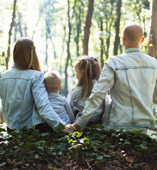 Two parents and their children with arms around one another out in nature