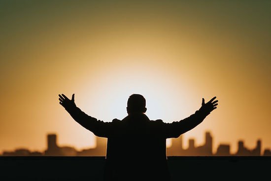 A silhouette of a man raising his arms to God and asking for victory over sin