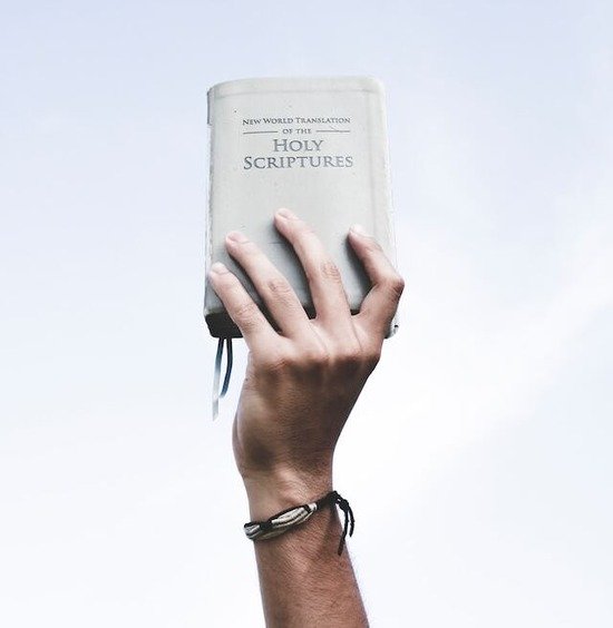A hand raising the Holy Scriptures, which Ellen White believed should be the foundation for true education