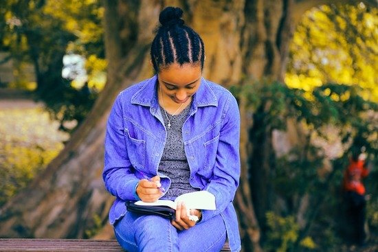 A young girl sitting outside and reading the Bible