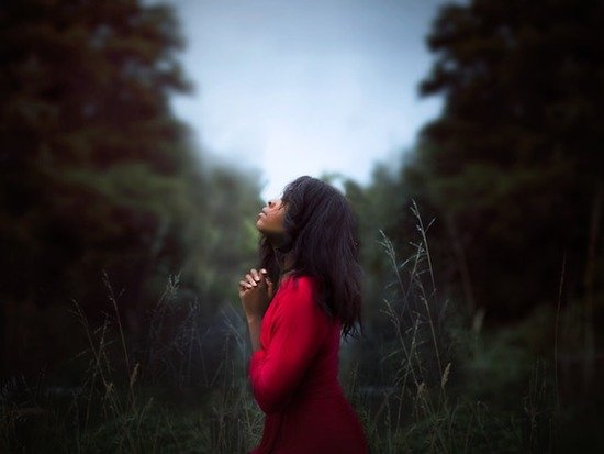 A woman folding her hands and praying for the outpouring of the Holy Spirit, which is prophesied to happen in the last days