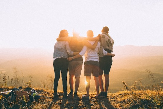 Friends with arms around each other, enjoying the sunset