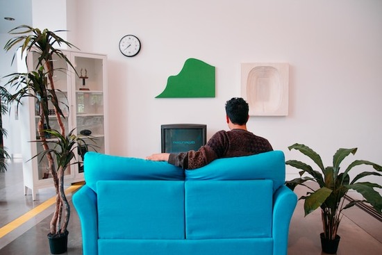 A man sitting on a couch and watching an Adventist film