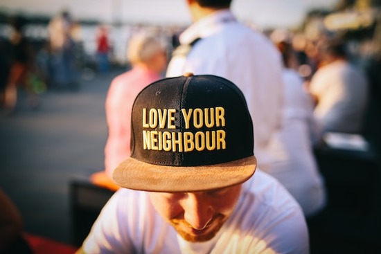 A young man with a hat that says, Love your neighbor 