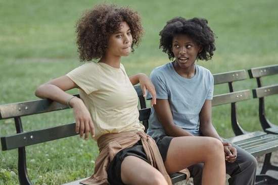 Two girls sitting on a park bench and discussing a conflict
