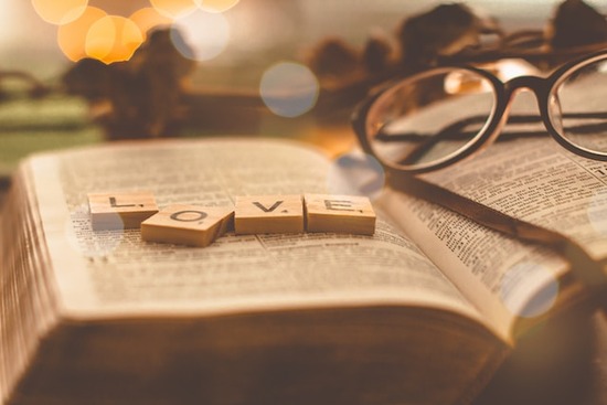 Scrabble letters spelling L-O-V-E on top of an open Bible