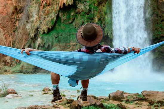 A man resting in a hammock at the base of waterfall on Sabbath