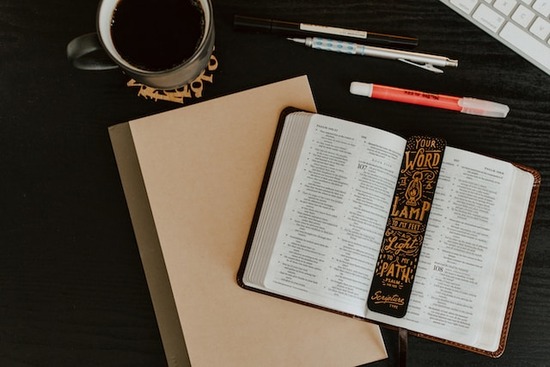  An open Bible on a desk full of Bible study materials