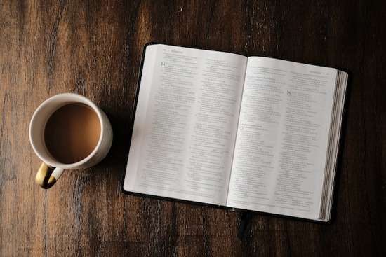 A Bible on a table next to a coffee mug showing resting way.