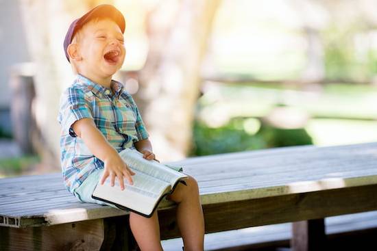 A little boy holding a Bible and smiling