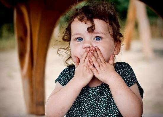 A little girl covering her mouth with her hands