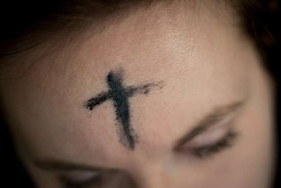 A person with an ash cross on her forehead for Ash Wednesday