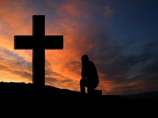 A man kneeling in front of a cross
