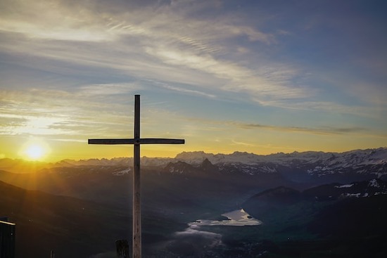 A cross illuminated by a sunset