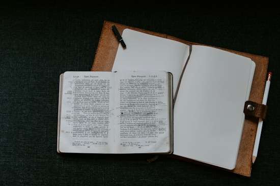 A very old Greek Bible on top of a blank notebook