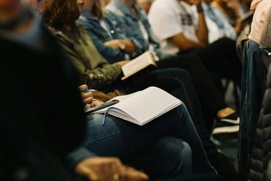 A group of people in church, listening and taking notes