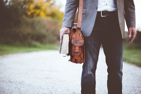 A man walking on a road and carrying a Bible