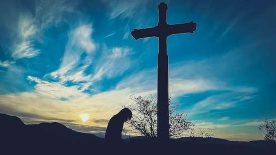 A man kneeling in front of a cross