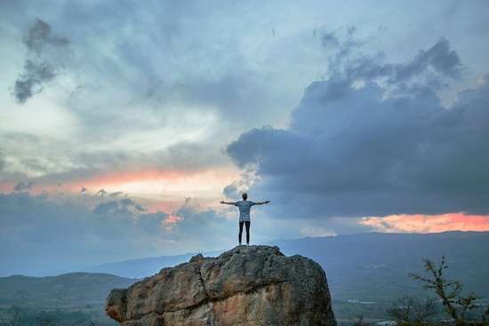 A man standing on a rock with arms outstretched