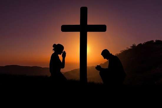 A woman and man kneeling at the cross