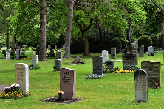A cemetery with tombstones on a green lawn
