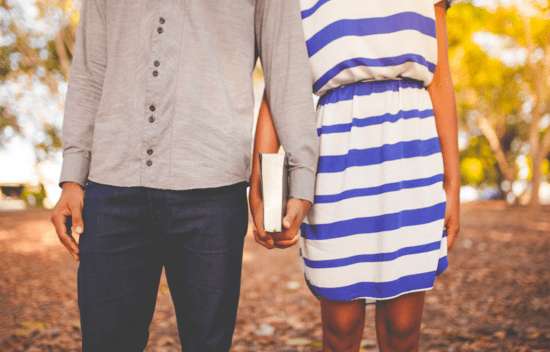 A couple holding a Bible together between them, showing how they're seeking God's will for their relationship