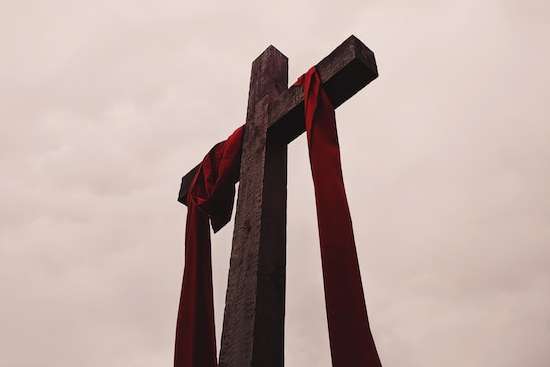 A cross with a red cloth draped around it, representing Jesus' death for us