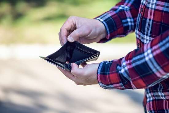 Hands hold open an empty wallet, suggesting financial struggles like those that Ellen and James White experienced