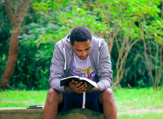 A man sitting and reading his Bible to draw close to Jesus