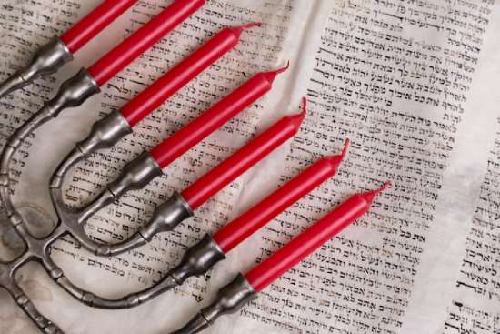 A menorah resting on top of Hebrew Scriptures