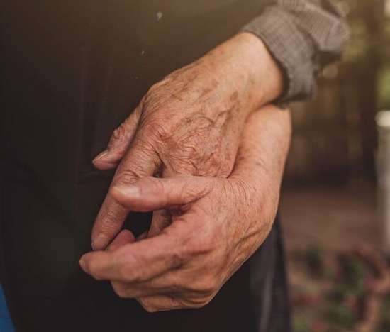 Wrinkled hands of an older couple clasped together