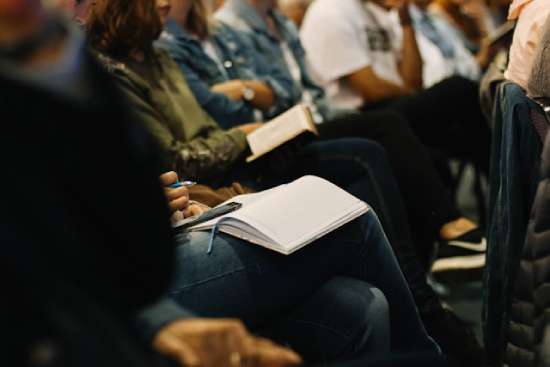 Adventist Church members sitting together at church, with their Bibles lying open on their laps.