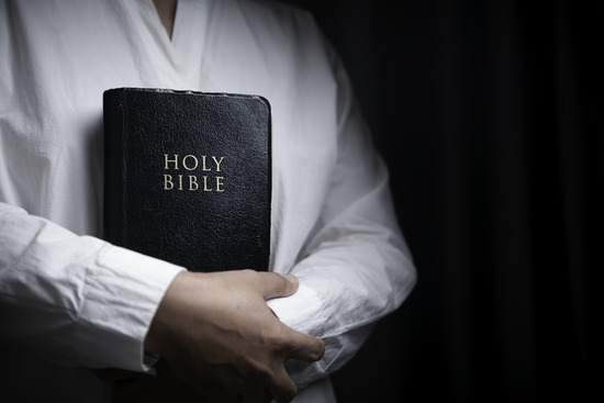 A woman holding a Bible to her chest