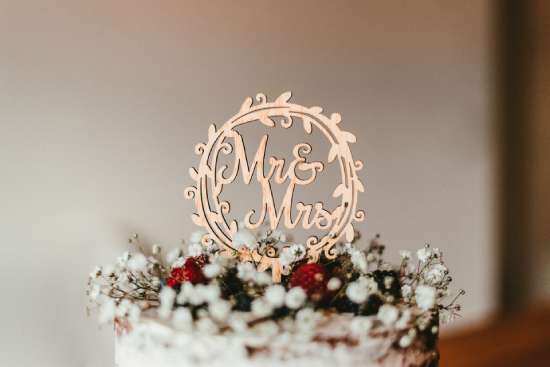 A cake topper reading, 'Mr. and Mrs.' sits on top of a white wedding cake.