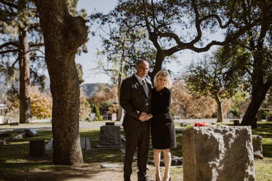 Couple dressed in black staring sadly at a gravestone in a cemetery a young couple stands at a gravesite to pay their respects to a deceased loved one