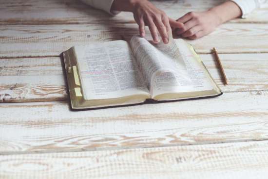 Hands turning through the pages of an open Bible